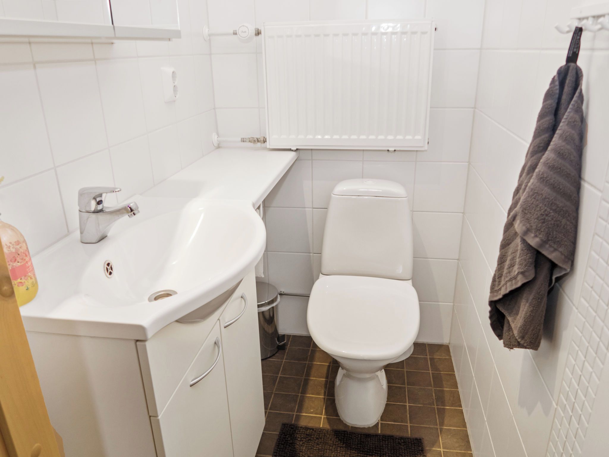 A small bathroom with a white sink, toilet, and radiator.