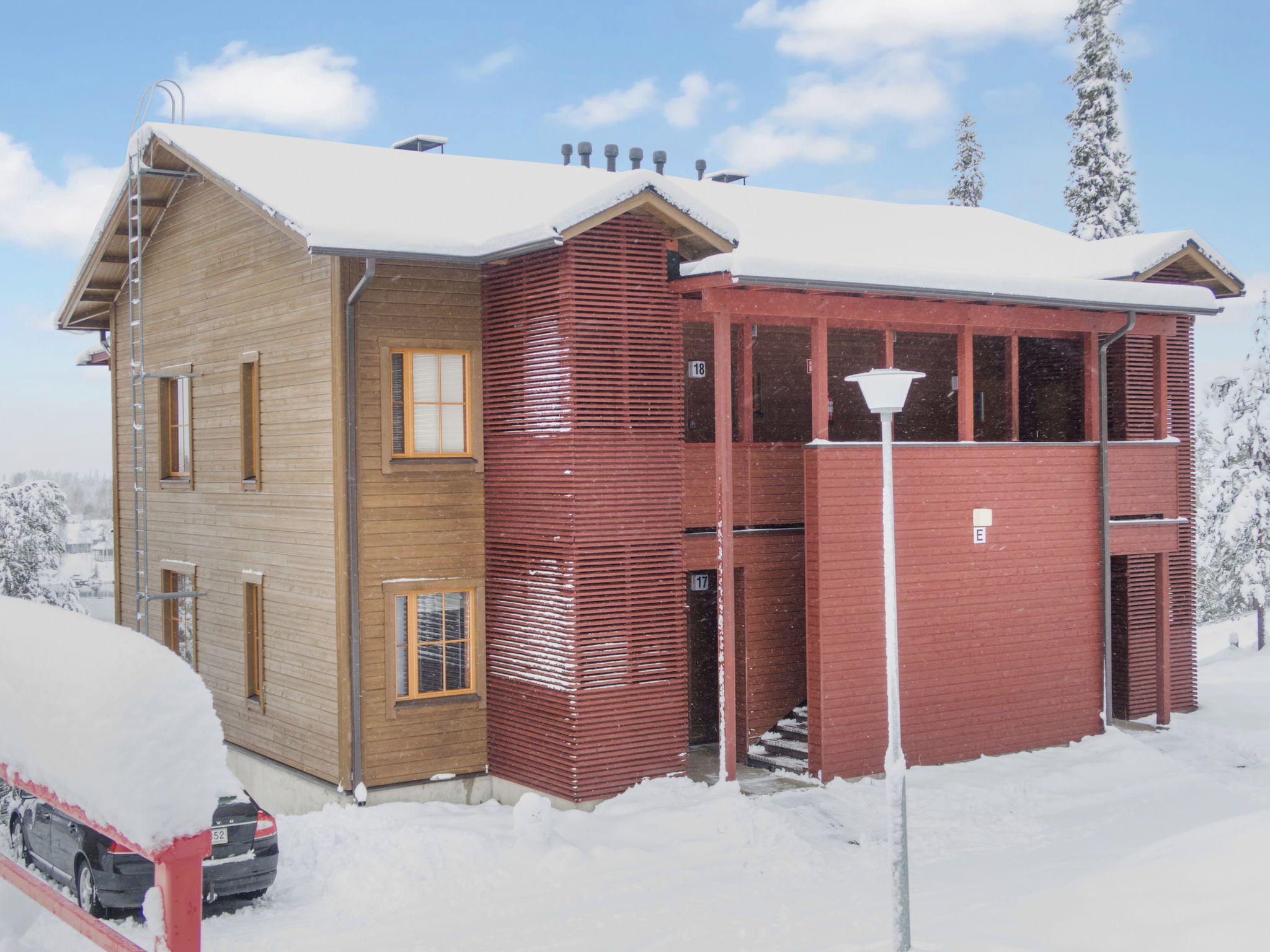 A two-story building with a wooden facade and a red section, surrounded by snow.