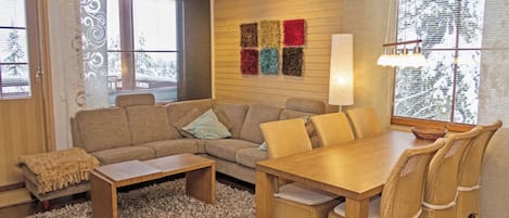 A cozy living room with a sofa, a coffee table, a dining table with chairs, and a rug.