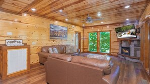 A wooden cabin interior with a sofa, fireplace, TV, and a painting on the wall.