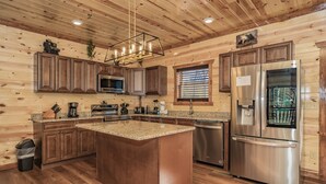 A modern kitchen with wooden paneling, stainless steel appliances, and a central island.