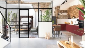 A modern kitchen with a red countertop, a dining area with a wooden table and chairs, and a staircase leading to an upper level. - Angie Neve Tzedek (Tel Aviv-Yafo)