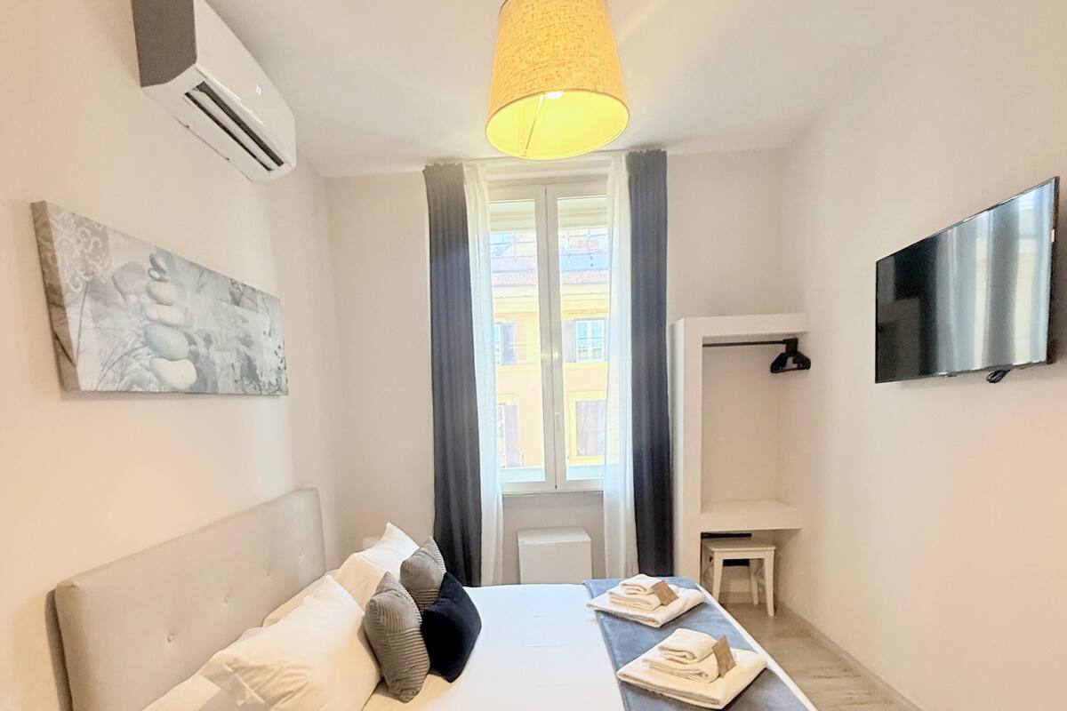 Ein modernes Schlafzimmer mit Bett, Nachttisch und Fernseher.