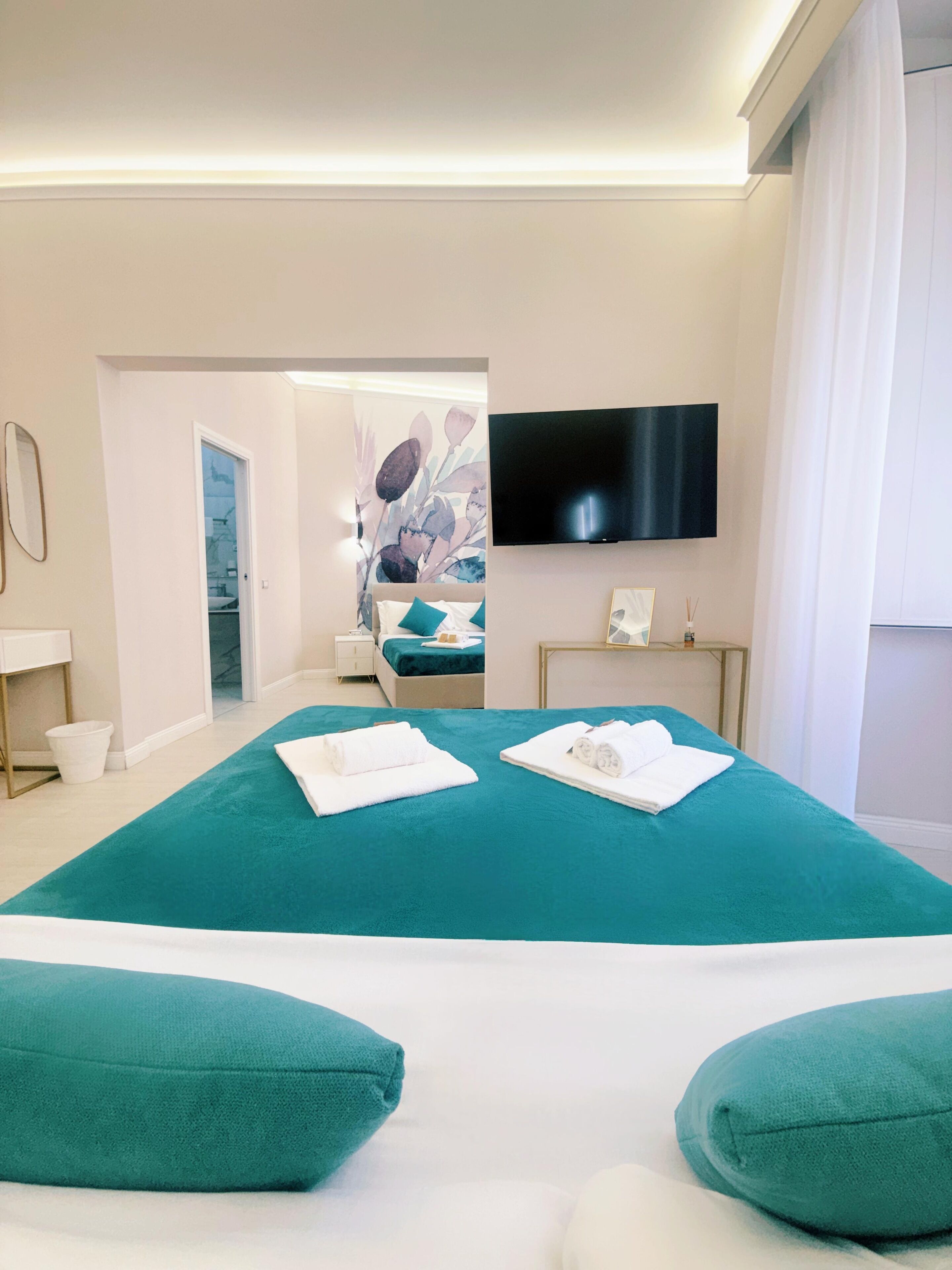 A hotel room with a large bed, a flat-screen TV, a desk, and a bathroom visible through an open door.
