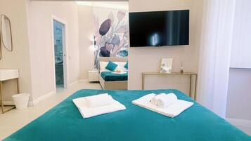 A hotel room with a large bed, a flat-screen TV, a desk, and a bathroom visible through an open door.