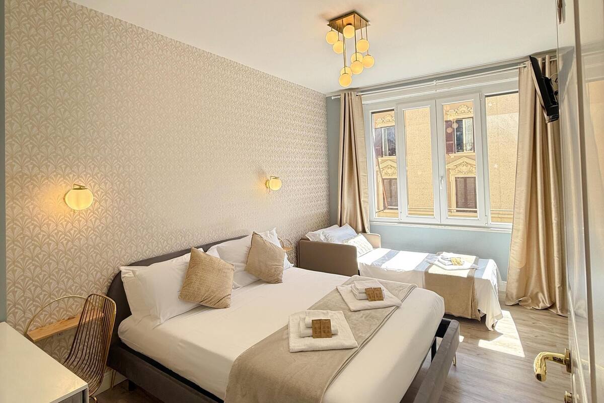 Ein Hotelzimmer mit einem großen Bett, Nachttischen, einem Schreibtisch und einem Fenster mit Vorhängen.