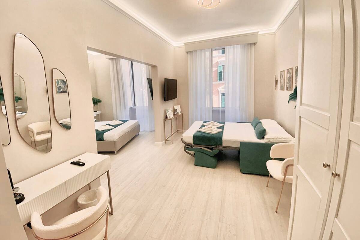 Ein modernes Hotelzimmer mit einem großen Bett, einer separaten Sitzecke, einem Schreibtisch und einem Badezimmer mit Toilette und Waschbecken.