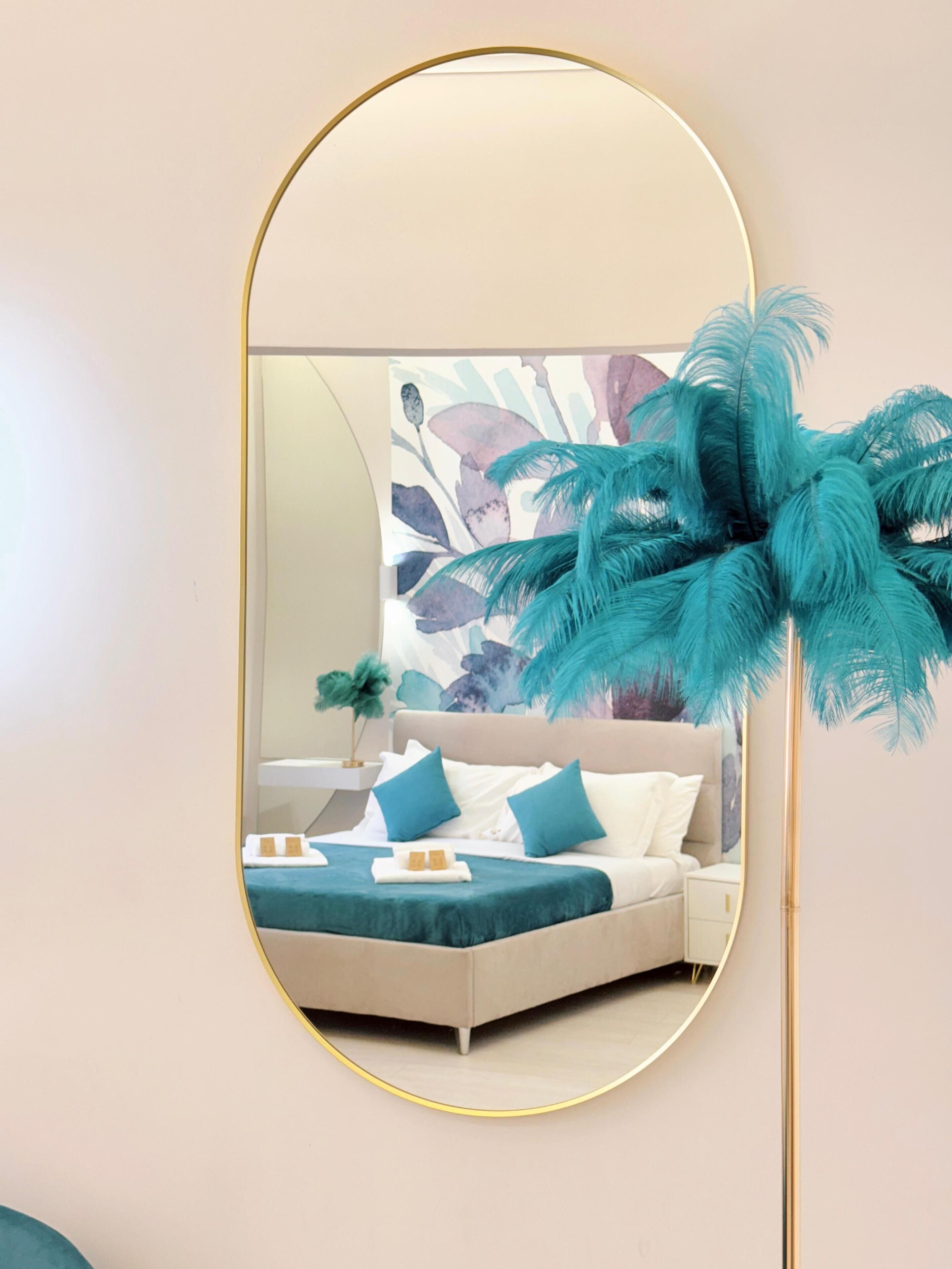 A bedroom with a bed, pillows, a nightstand, and a mirror.