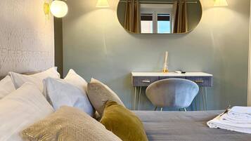 A hotel room with a large bed, a desk with a mirror, and two wall-mounted lights.