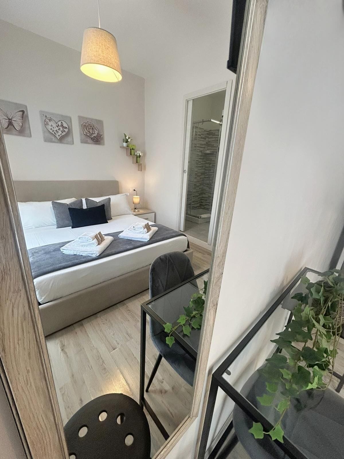 A modern bedroom with a bed, bedside table, lamp, and a glass shower enclosure.