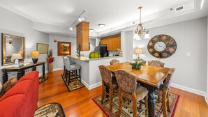 Une cuisine moderne avec des meubles en bois, un îlot central et un coin repas comprenant une table en bois et des chaises à motifs.