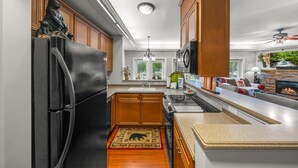 Une cuisine moderne avec des meubles en bois, un réfrigérateur noir, un four encastré et une cheminée en pierre.