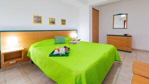 Une chambre d’hôtel avec un grand lit, une tête de lit en bois, une table de chevet, une commode et un miroir au mur.