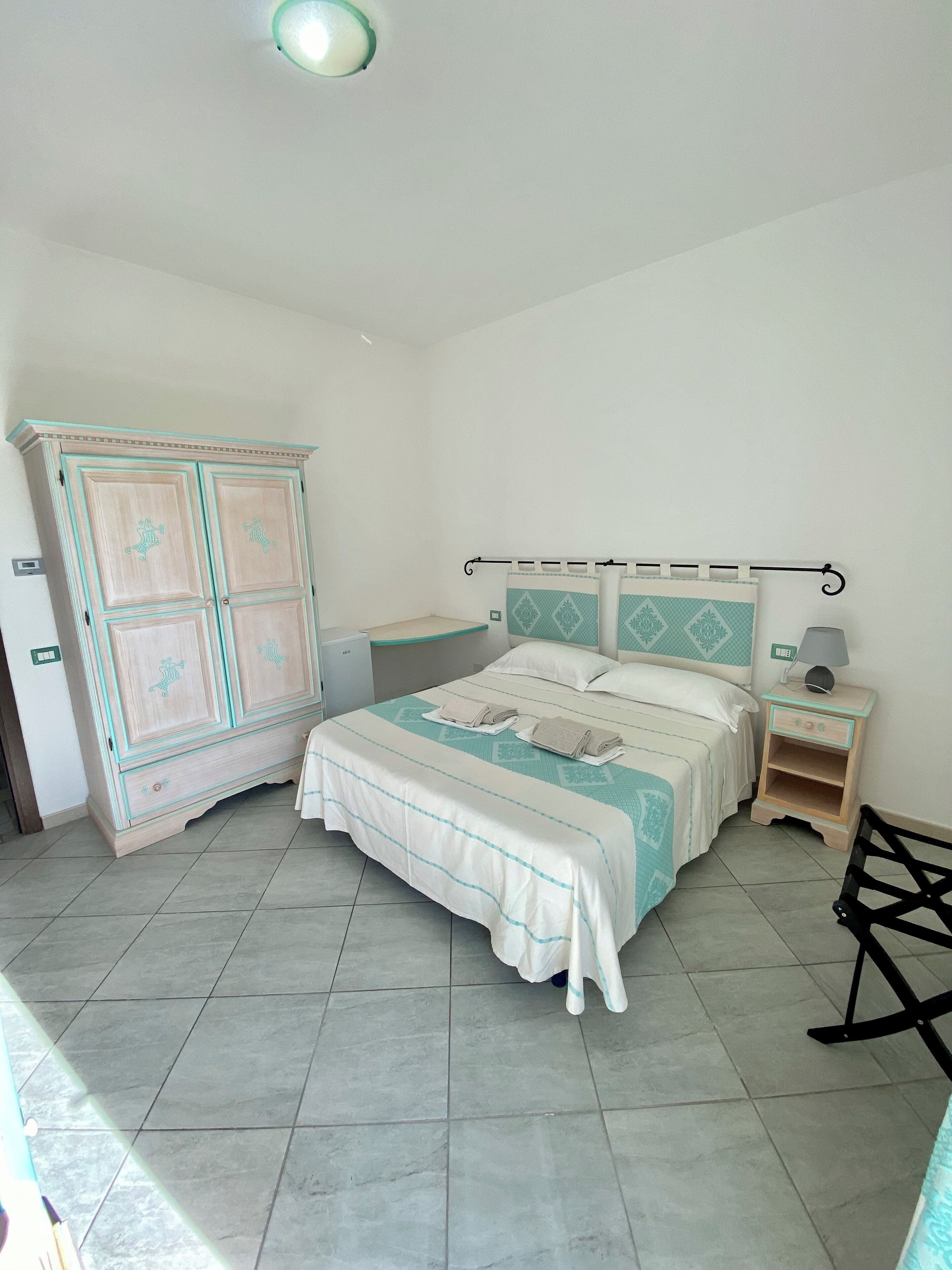 Un dormitorio con cama, mesita de noche, armario y una silla.