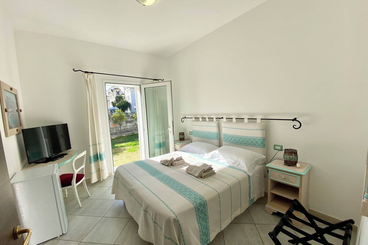 A hotel room with a bed, a TV, a desk, and a chair.