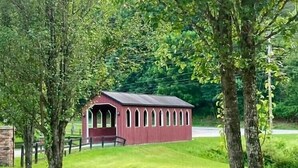 A small red building with arched windows, surrounded by trees and grass. - Granny Squirrel Getaway (Andrews)
