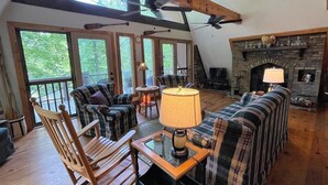 A cozy loft-style living room with a fireplace, wooden beams, and large windows. - Granny Squirrel Getaway (Andrews)