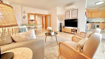 A modern living room with a sofa, armchairs, a coffee table, and a TV.
