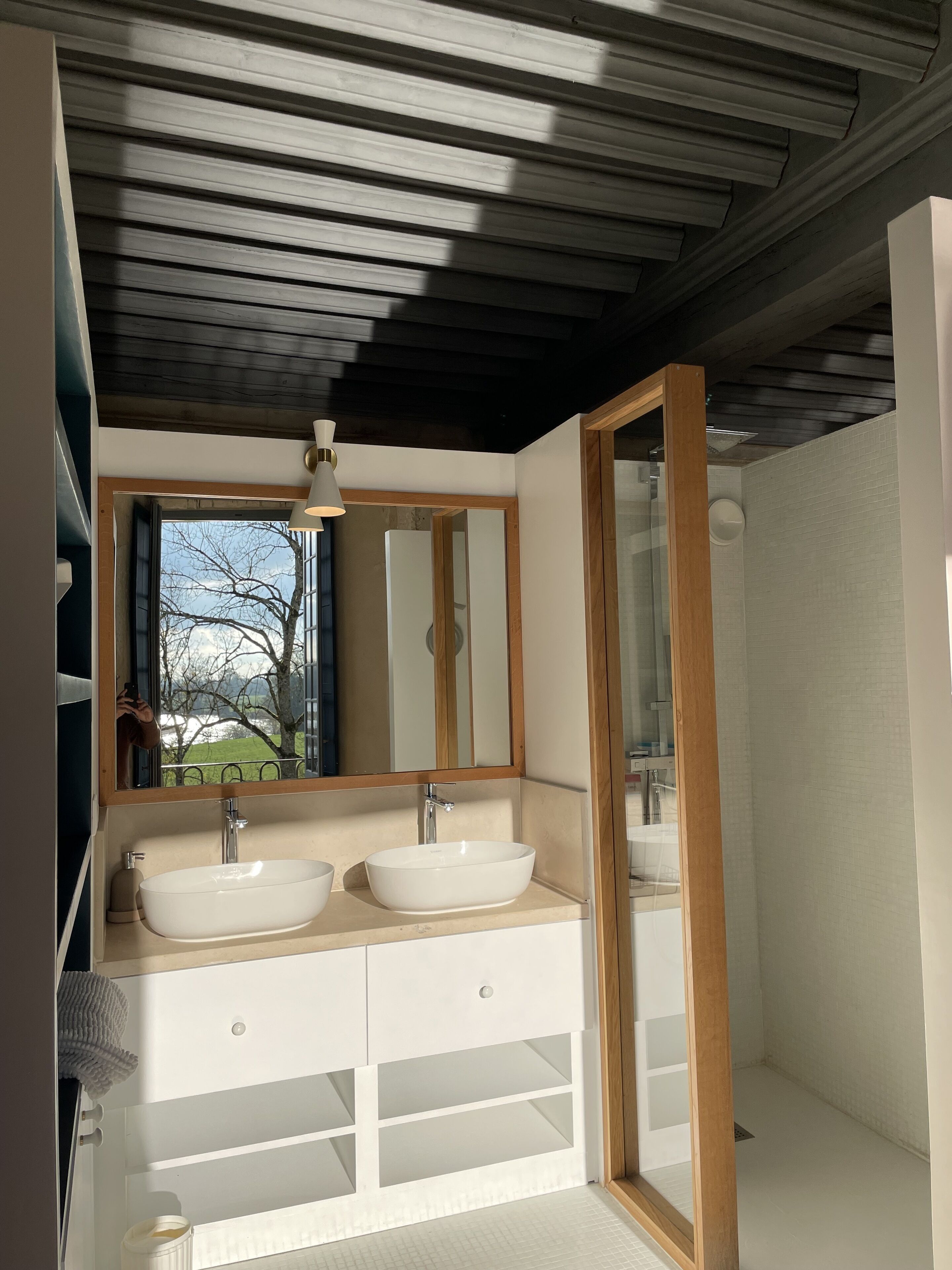 A modern bathroom with two sinks, a large mirror, and a shower area.