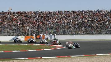 A motorcycle race on a track with a large crowd in the background.