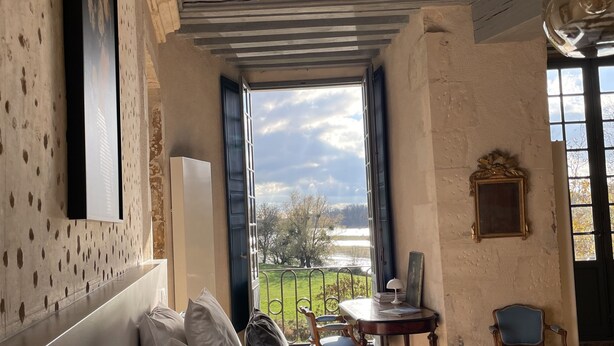 A bedroom with a large bed, a view of the outdoors, a dining table, and a chair. - Château de Meauce (Saincaize-Meauce)