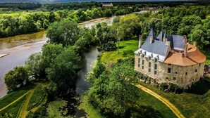 A historic stone building with a turret and a river flowing through a lush green landscape. - Château de Meauce (Saincaize-Meauce)