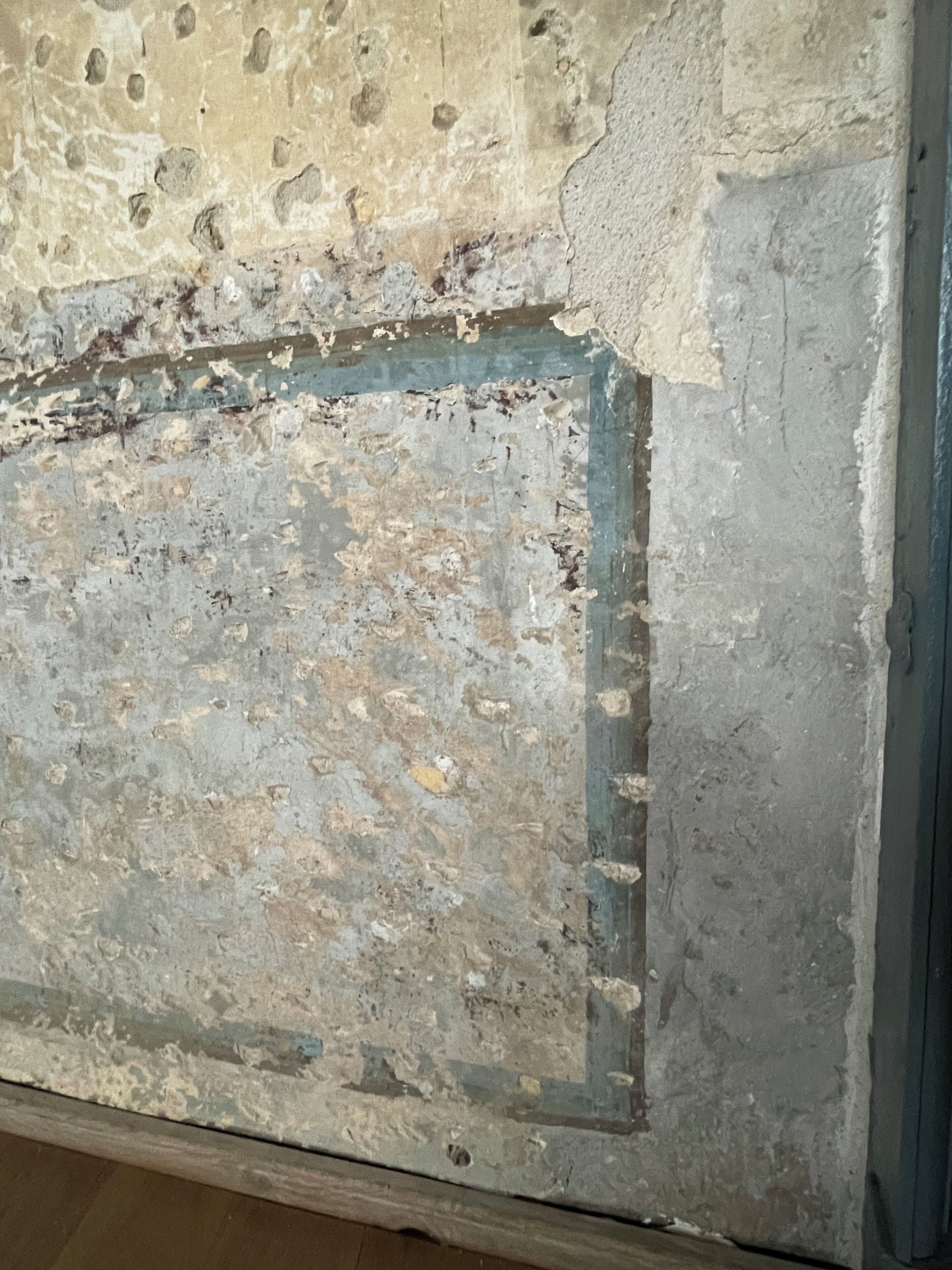 A close-up of a textured wall with visible wear and patches.