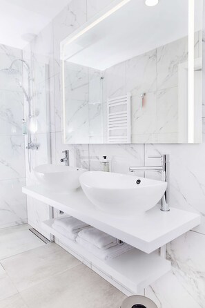 Une salle de bain moderne avec un grand lavabo blanc, une douche à parois de verre et un grand miroir.
