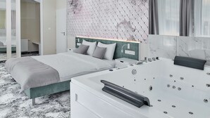 Et moderne hotelværelse med en stor seng, et separat opholdsområde, et badekar og udsigt over byen.