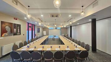 A conference room with a long table, chairs, and a whiteboard.