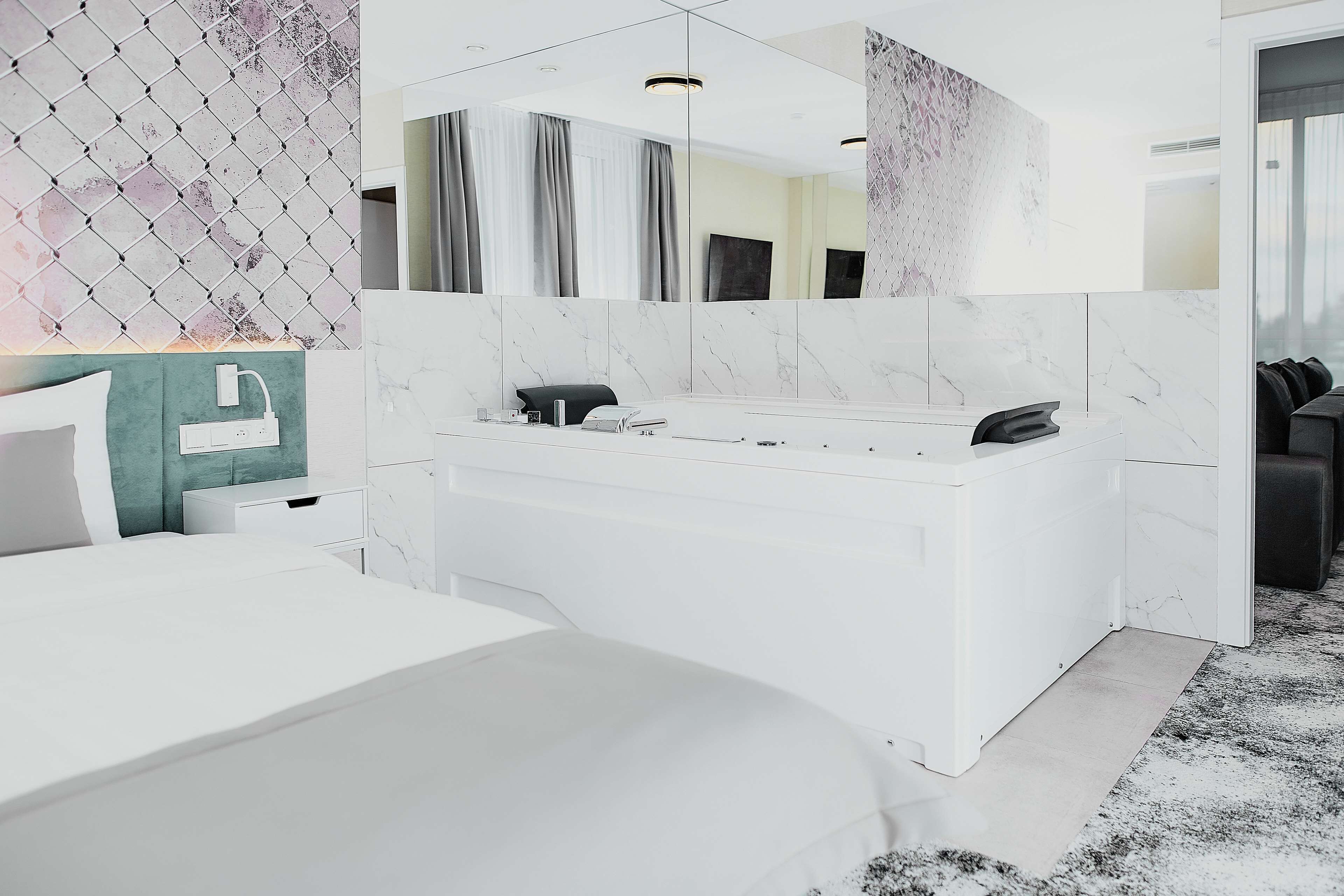 Un baño moderno con tocador blanco, un espejo grande y salpicadero de mármol.