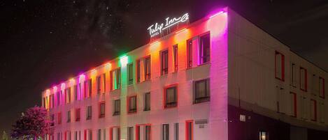 Un hotel con fachada moderna, varias ventanas y un letrero de neón.