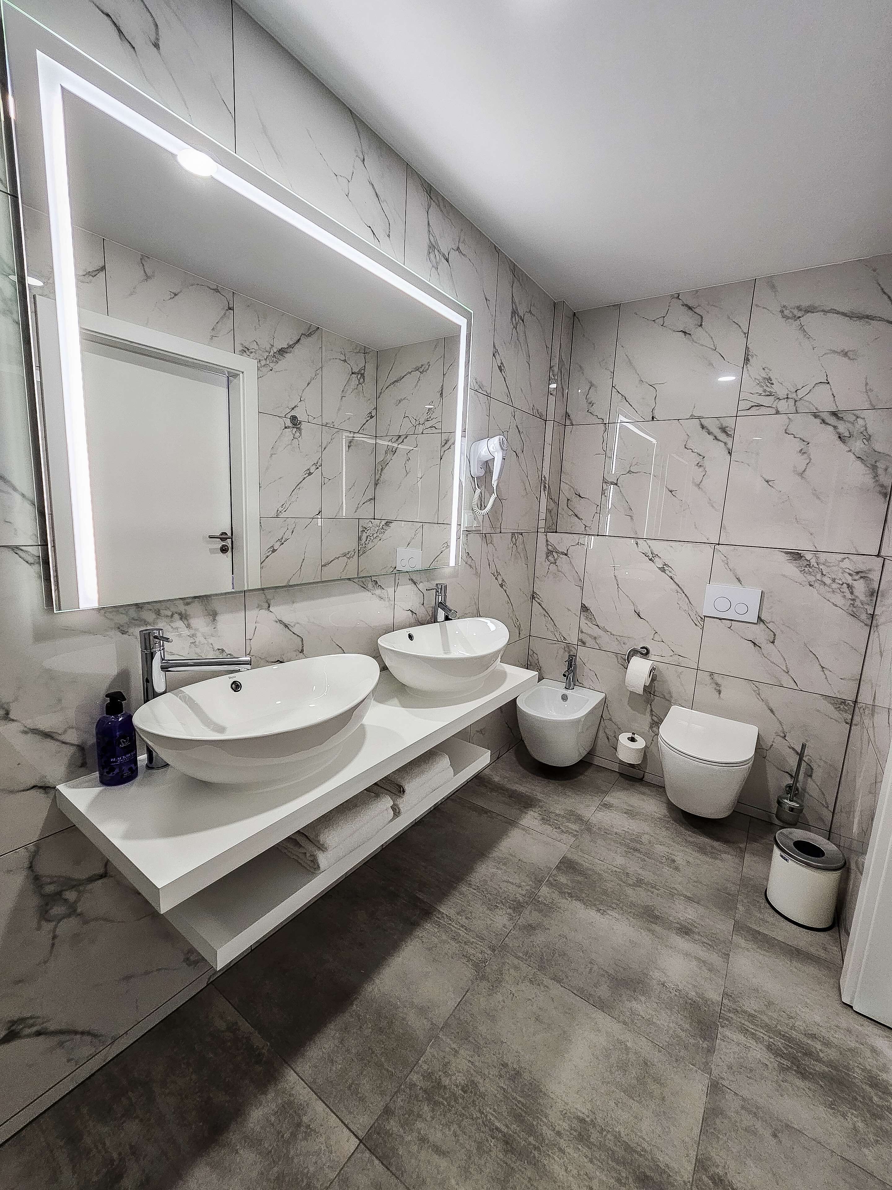 Une salle de bain moderne avec deux lavabos, un bidet et des toilettes.