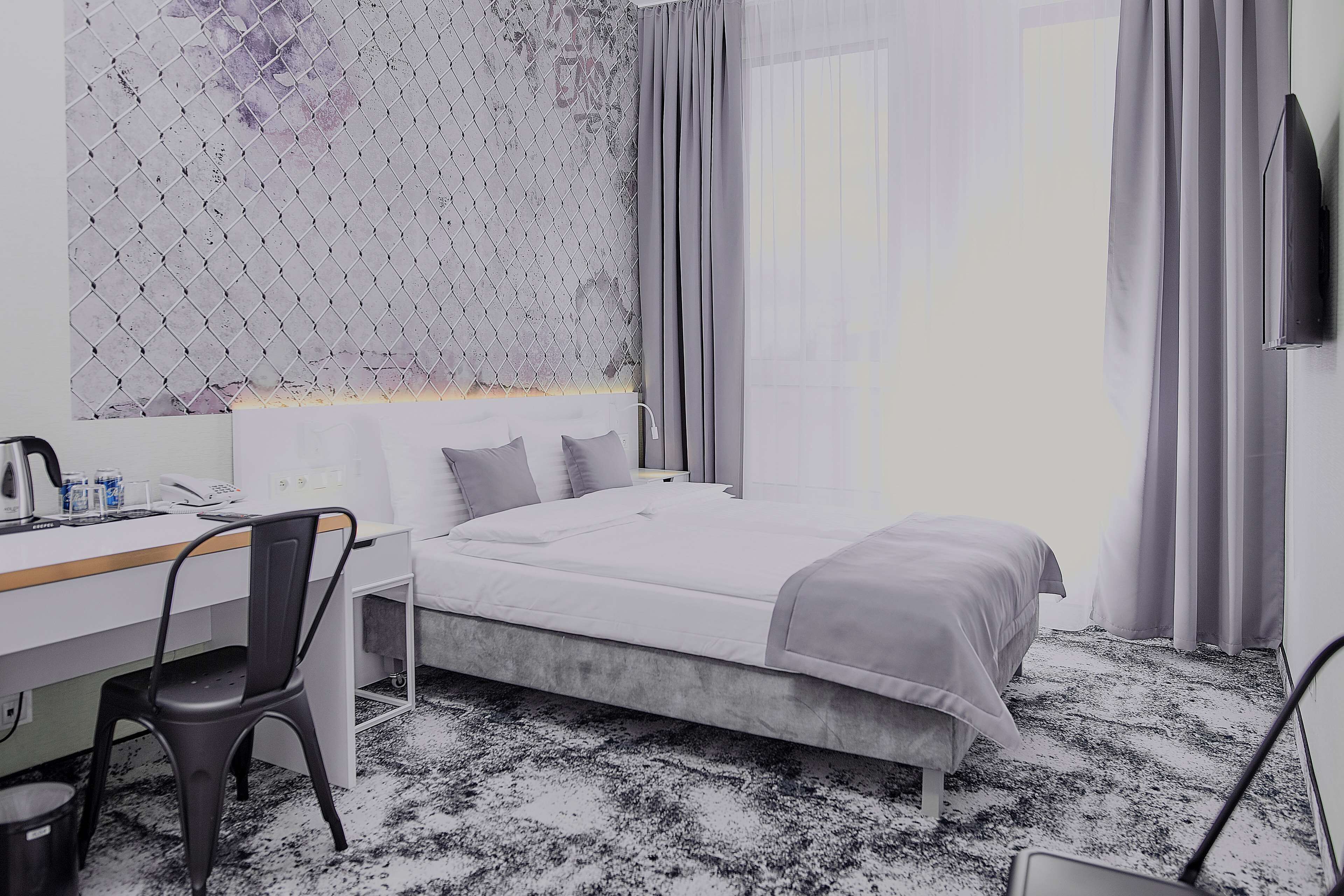 Una habitación de hotel con una cama, un escritorio, una silla y un televisor.