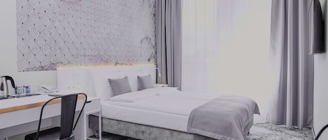 Una habitación de hotel con una cama, un escritorio, una silla y un televisor.