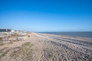 Stroll along the pebbled beach to the sea, surrounded by charming coastal buildings with white walls and dark roofs.