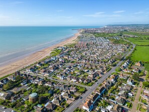 Vista aérea de una zona residencial costera con casas, caminos y una playa.
