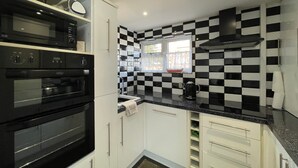 Une cuisine compacte avec un dosseret à carreaux noirs et blancs, une fenêtre et une hotte noire.