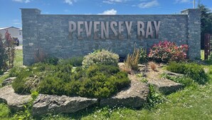 A stone sign with "PEVENSEY BAY" written on it, surrounded by landscaped greenery and rocks. - 27 Tower View Pevensey Bay Holiday Park Beach (Pevensey)