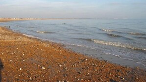 A pebbled beach with calm waves and a clear sky. - 27 Tower View Pevensey Bay Holiday Park Beach (Pevensey)