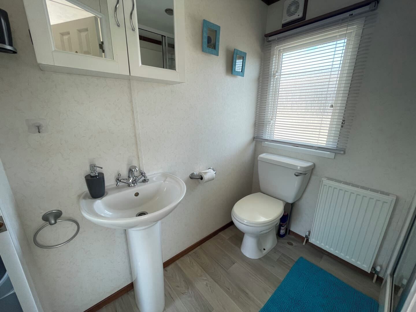 A bathroom with a white sink, toilet, and window with blinds.