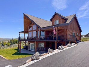 Una casa grande de madera con balcón, base de piedra y una bandera.