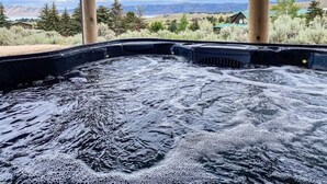 A hot tub with a view of mountains and houses in the background. - Nature Calls- Log home, hot tub & Ideal Beach Pass (Garden City)
