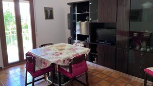 A dining area with a table set for four, surrounded by dark wood cabinets, a chandelier, and a sliding glass door leading to a balcony. - Montefortino Sibillini House B&B (Montefortino)