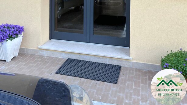 A building entrance with a glass door, a mailbox, and a number '18' on the wall. - Montefortino Sibillini House B&B (Montefortino)