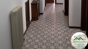 A hallway with patterned floor tiles, a radiator, a telephone, and a door leading to another room. - Montefortino Sibillini House B&B (Montefortino)