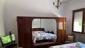 A room with a bed, a wardrobe, a television, and a window with blinds. - Montefortino Sibillini House B&B (Montefortino)