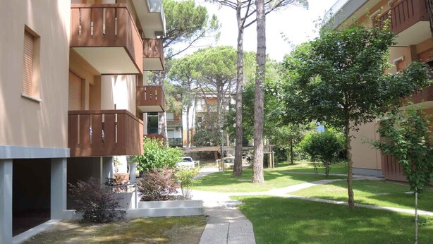 Un patio con un sendero, árboles y un edificio con balcones.