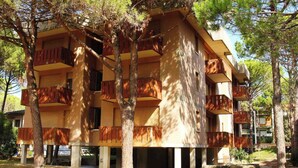 Un edificio de varios pisos con balcones, rodeado de árboles.