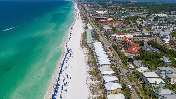 Luftaufnahme einer Küstenstadt mit einem langen Strand, Gebäuden an der Uferlinie und freiem Blick auf den Ozean.